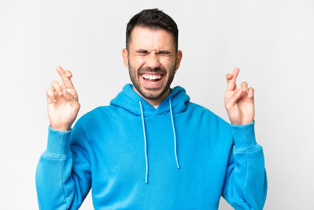 Young handsome caucasian man over isolated white background with fingers crossing