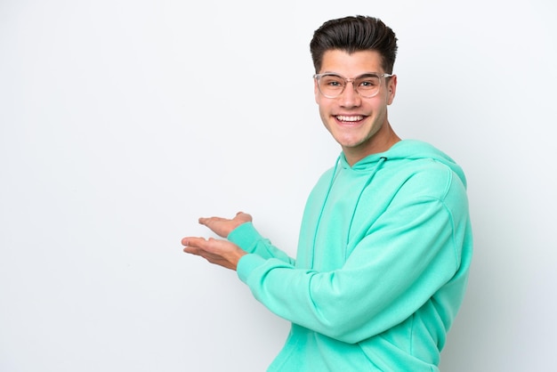 Young handsome caucasian man isolated on white bakcground extending hands to the side for inviting to come