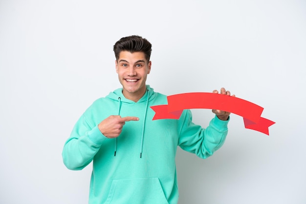 Young handsome caucasian man isolated on white bakcground holding an empty placard with surprised expression