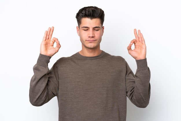 Young handsome caucasian man isolated on white bakcground in zen pose