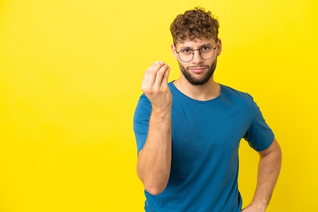 Young handsome caucasian man isolated on yellow background making italian gesture