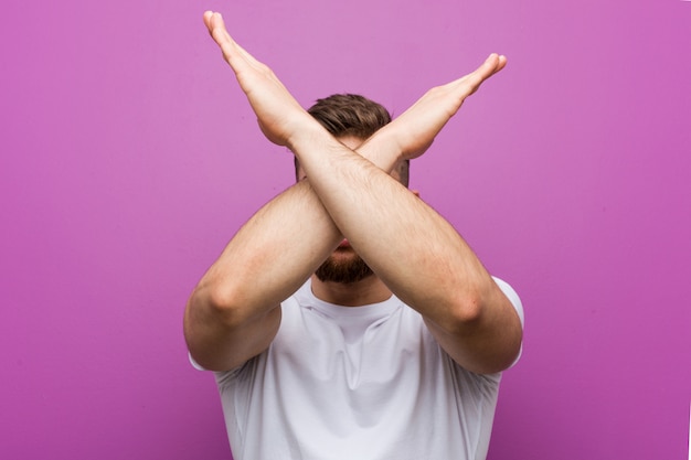 Young handsome caucasian man keeping two arms crossed, denial .