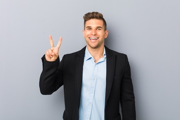 Young handsome caucasian man showing victory sign and smiling broadly.