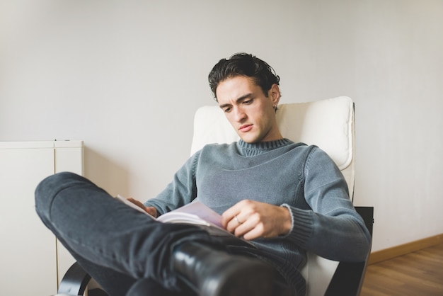 Young handsome caucasian man sitting on the armchair