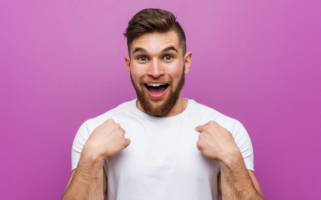 Young handsome caucasian man surprised pointing at himself, smiling broadly.