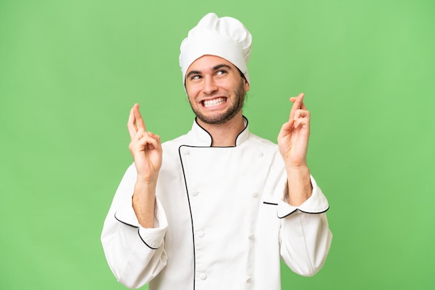손가락이 교차하는 고립된 배경 위에 있는 젊고 잘생긴 요리사 남자