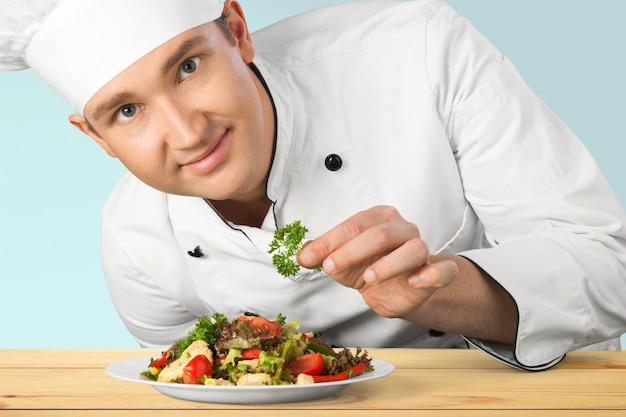 Young handsome chef showing his dish on colorful background