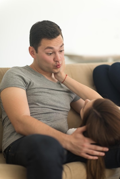 若いハンサムなカップルは彼らの豪華な家の別荘でソファに抱き締めることを楽しんでいます