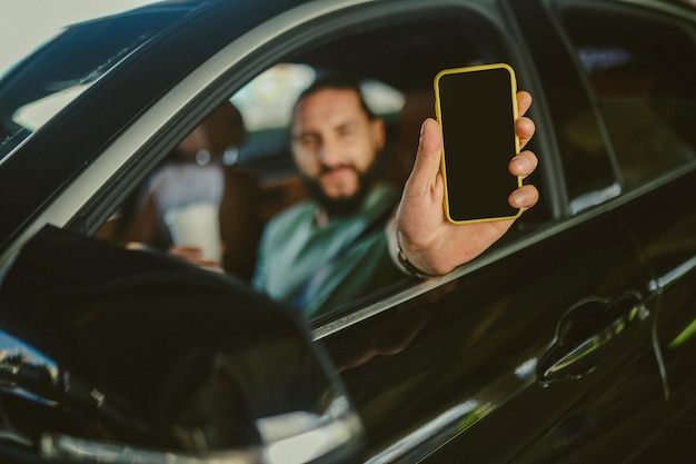 Young handsome darkhaired man holding a phone and driving a car