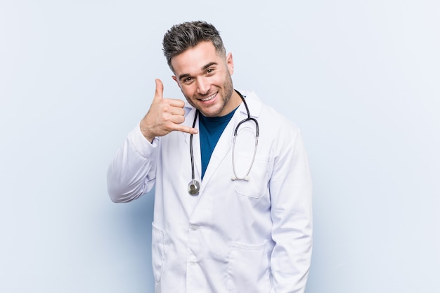 Young handsome doctor man showing a mobile phone call gesture with fingers.