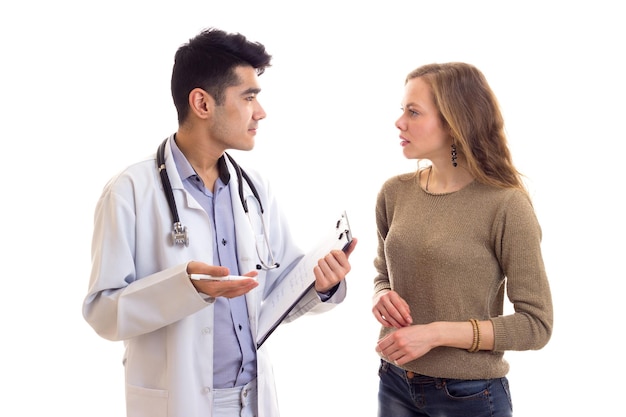 Young handsome doctor in white gown with stethoscope looking throw papers with young nice woman