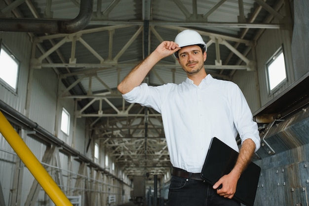 A young handsome employee of a modern factory in a white hard