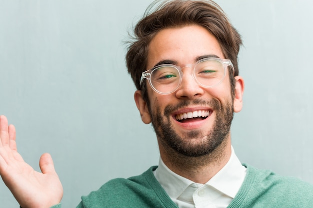 Young handsome entrepreneur man face closeup laughing and having fun, being relaxed and cheerful, feels confident and successful