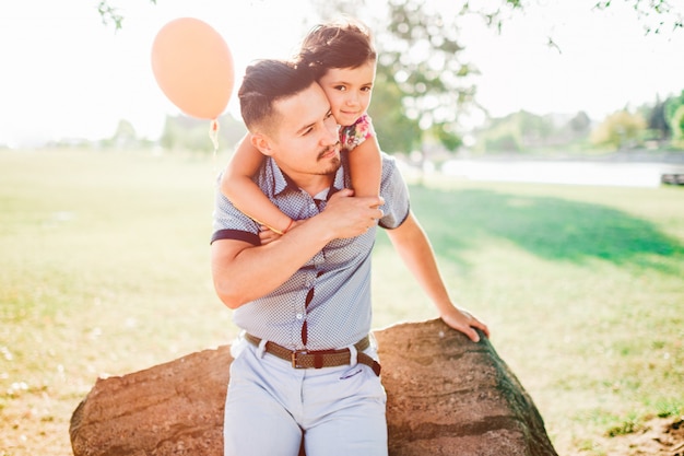 Young handsome father holding his little cute daughter outdoor in summer park