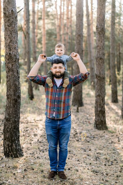 Foto giovane bel padre e figlio, che indossano abiti casual alla moda, divertendosi nel parco d'autunno