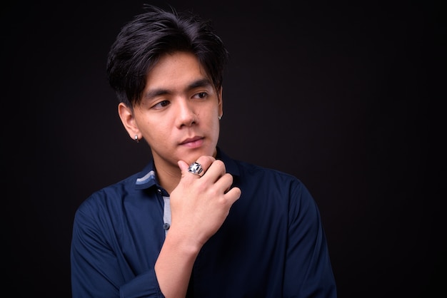  young handsome Filipino man against black wall