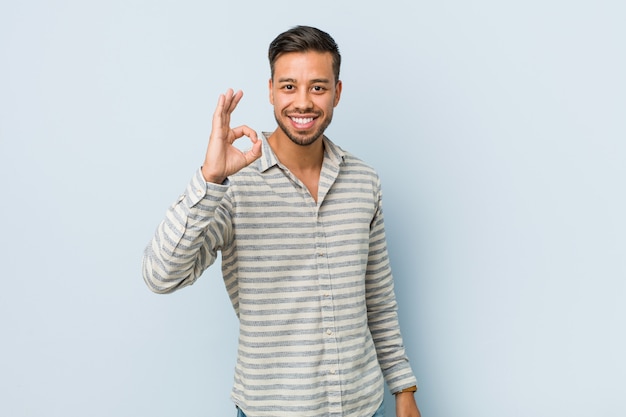 Young handsome filipino man cheerful and confident showing ok gesture.