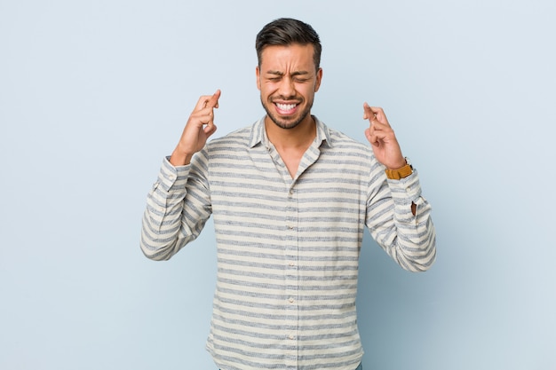 Young handsome filipino man crossing fingers for having luck