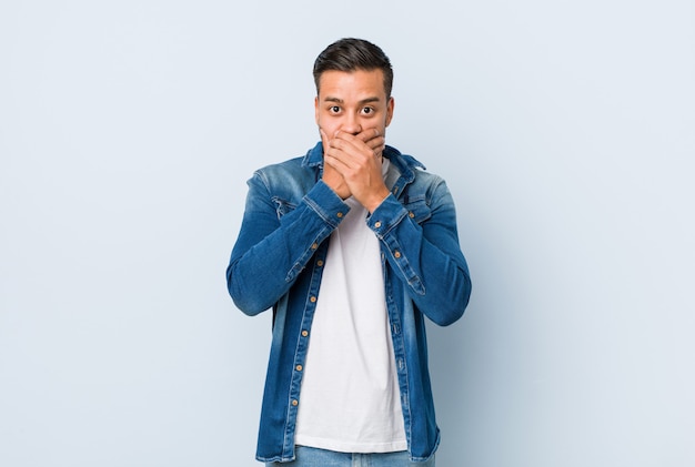 Young handsome filipino man shocked covering mouth with hands.