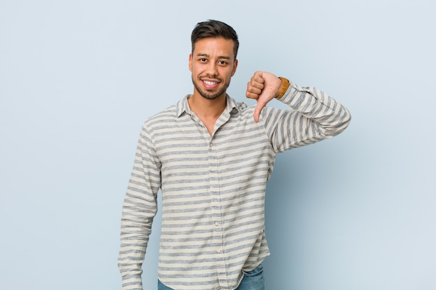 Young handsome filipino man showing a dislike gesture, thumbs down. Disagreement concept.