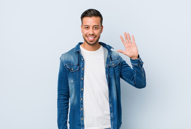 Young handsome filipino man smiling cheerful showing number five with fingers.