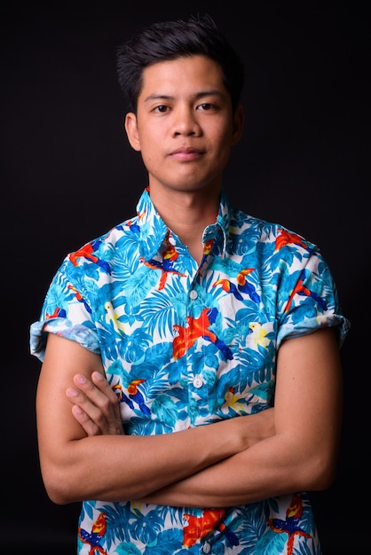  young handsome Filipino tourist man ready for vacation against black wall