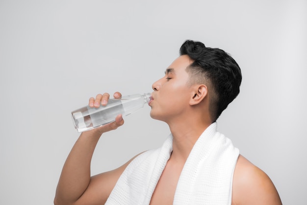 Young handsome fit man drinks water / male model with bottle of water