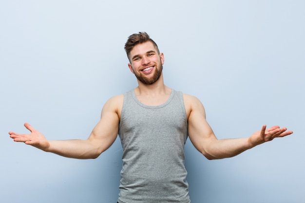 Young handsome fitness man showing a welcome expression.