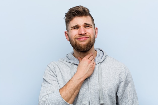 Young handsome fitness man suffers pain in throat due a virus or infection.