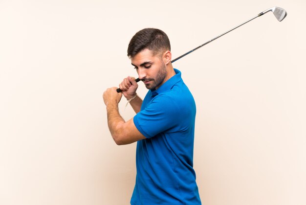 Young handsome golfer man over isolated wall