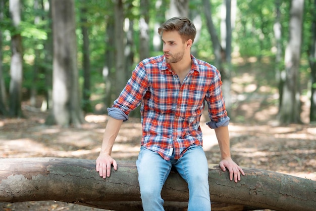 Foto il giovane bel ragazzo in camicia a scacchi si rilassa all'aperto