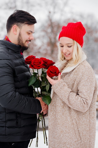 Young handsome guy giving a woman a bouquet of roses on valentine's day