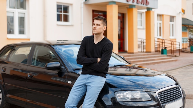 Young handsome guy near a black car