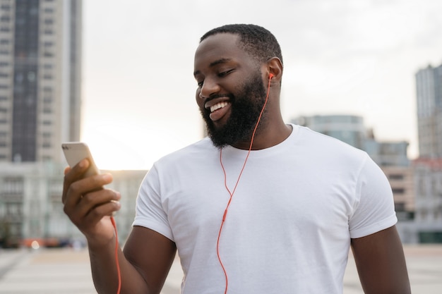 Young handsome guy using mobile phone communication looking at digital screen walking on the street