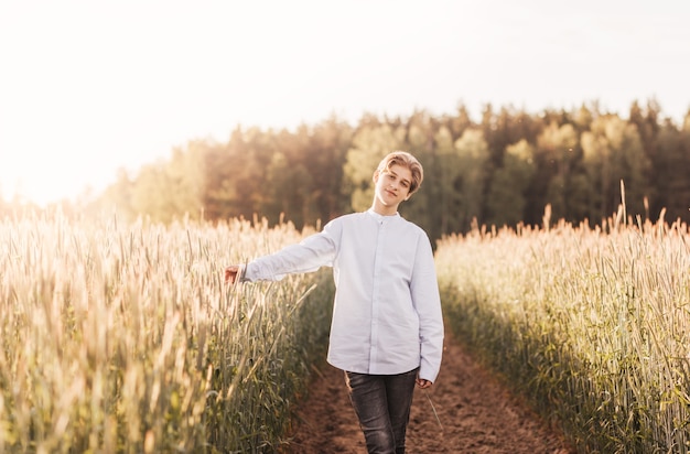 Young handsome guy walks on a wheat field