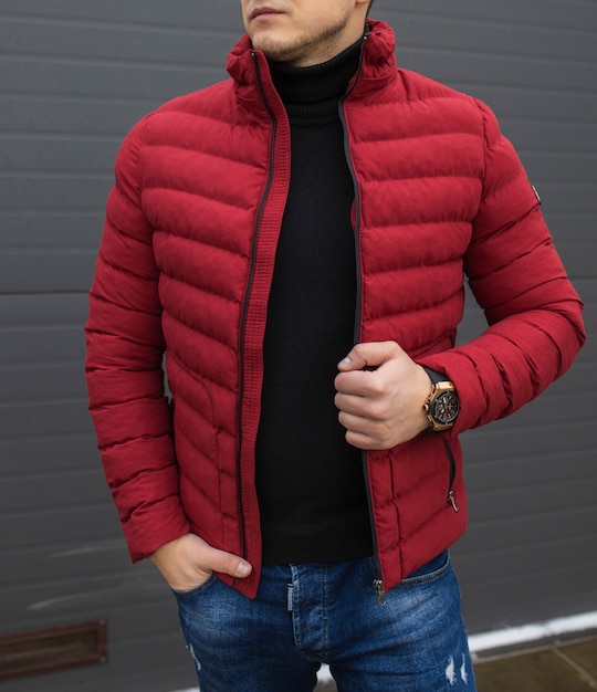 Young handsome guy in a warm knitted clothes against a space of black wall