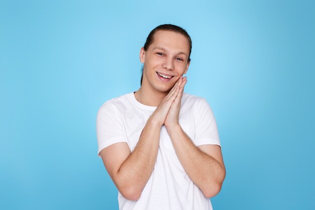 Young handsome guy in white shirt smiling isolated on blue background. Human emotions, facial expressions