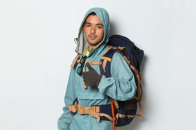 Young handsome hiker man with backpack showing a thumbs up ok gesture on white background