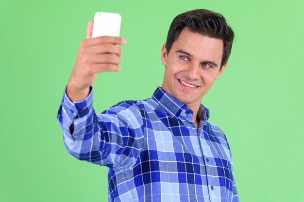  young handsome hipster man against green wall