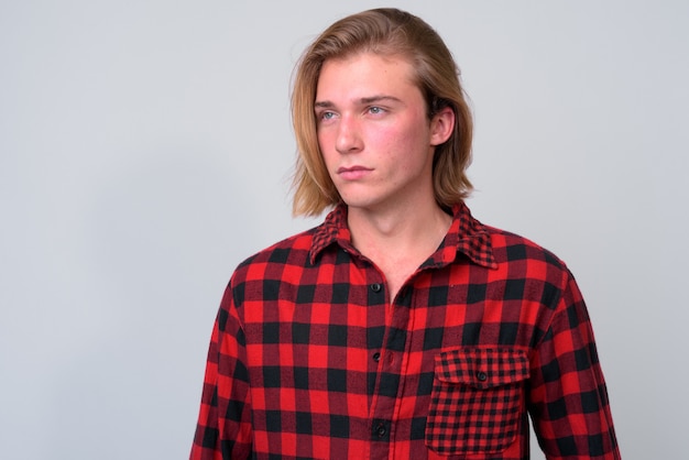 young handsome hipster man with long blond hair against white wall