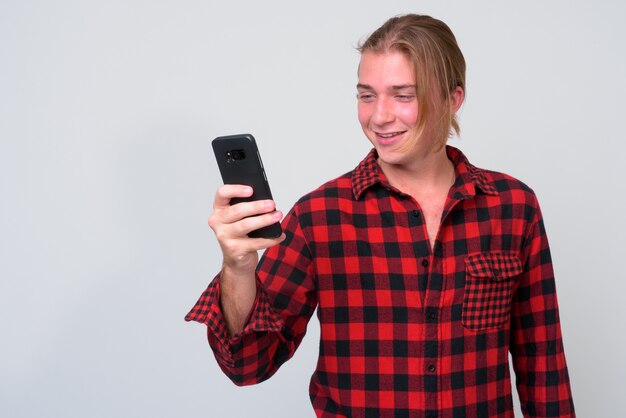 young handsome hipster man with long blond hair against white wall