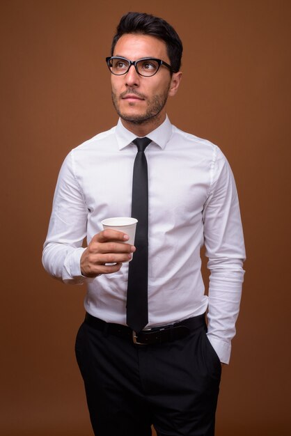Молодой красивый латиноамериканский бизнесмен на коричневом фоне