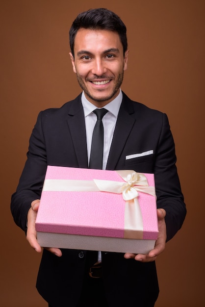 Young handsome Hispanic businessman against brown background