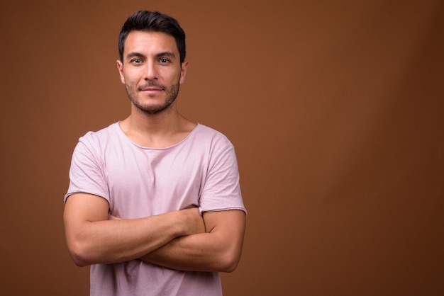Young handsome Hispanic man against brown background