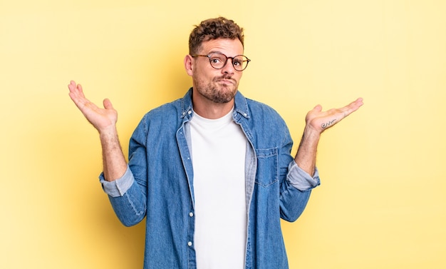 Young handsome hispanic man feeling puzzled and confused, doubting, weighting or choosing different options with funny expression