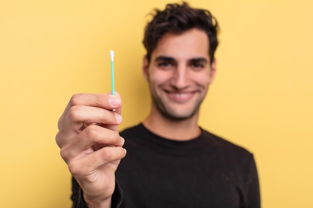 Young handsome hispanic man holding a cotton bud