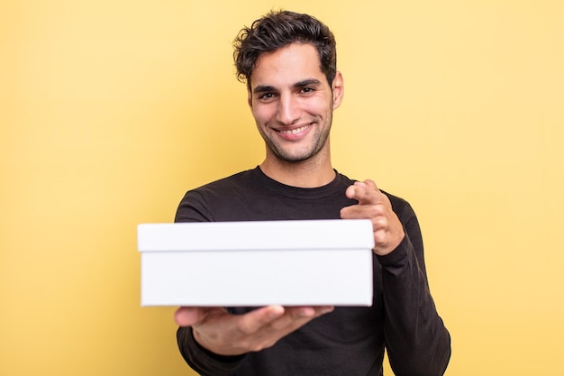 Young handsome hispanic man holding a white box