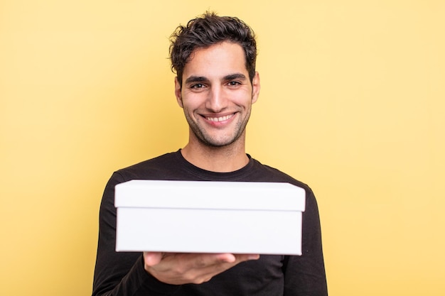 Young handsome hispanic man holding a white box