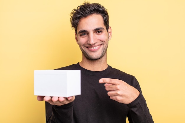 Young handsome hispanic man holding a white box