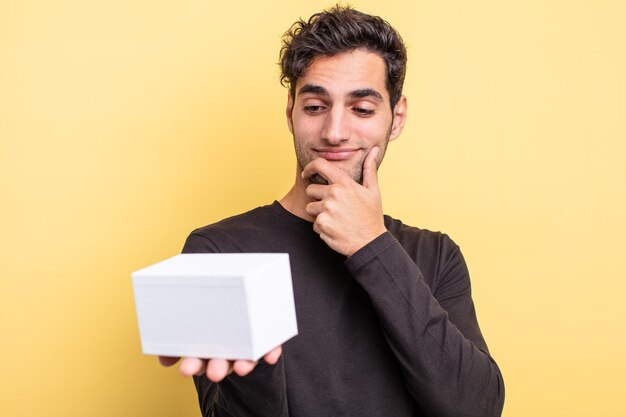 Young handsome hispanic man holding a white box